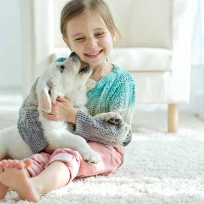 little girl with puppy on plush white carpet in living room